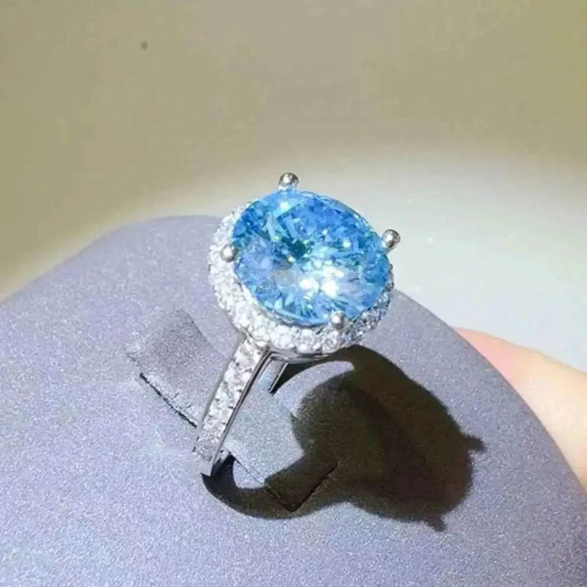 1 Carat Moissanite ring with a round blue stone surrounded by small clear stones on a silver band