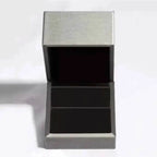 Open metallic silver jewelry box with black cushioned interior designed to hold a 1 Carat Moissanite ring.