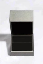 Open silver metal jewelry box with black velvet interior, designed to hold a 10.5 Carat Moissanite ring securely.