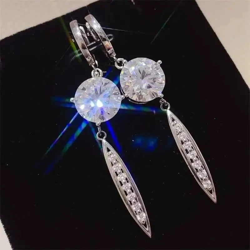 Dangle earrings with large round clear stones and elongated silver drops, made of 925 sterling silver and 10 Carat Moissanite.
