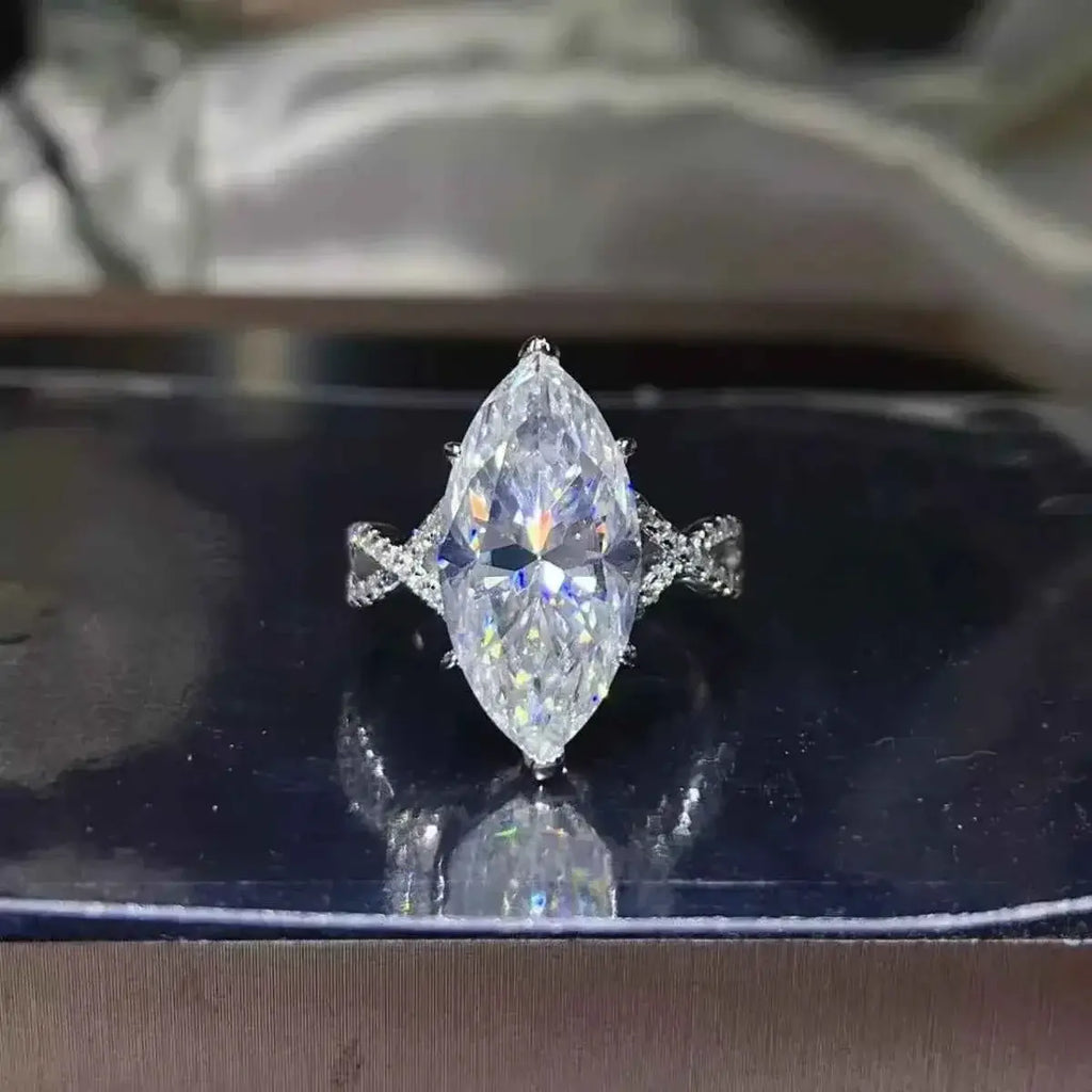 10 Carat Moissanite ring with a large marquise-cut stone set in silver with a twisted band design and small accent stones.