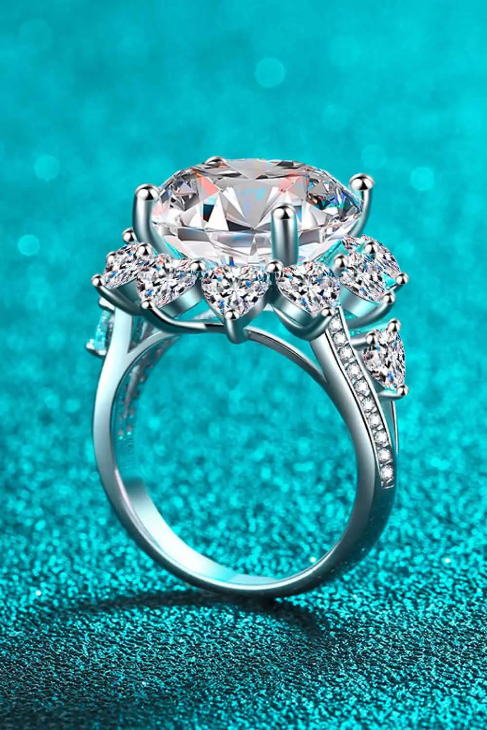 Flower-shaped silver ring featuring a large clear Carat Moissanite center stone surrounded by smaller teardrop-shaped stones.