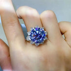 925 sterling silver ring with a large round blue 10 Carat Moissanite center stone surrounded by smaller clear stones