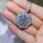 10 Carat Moissanite round silver pendant necklace with zircon accent stones in intricate floral design held in hand