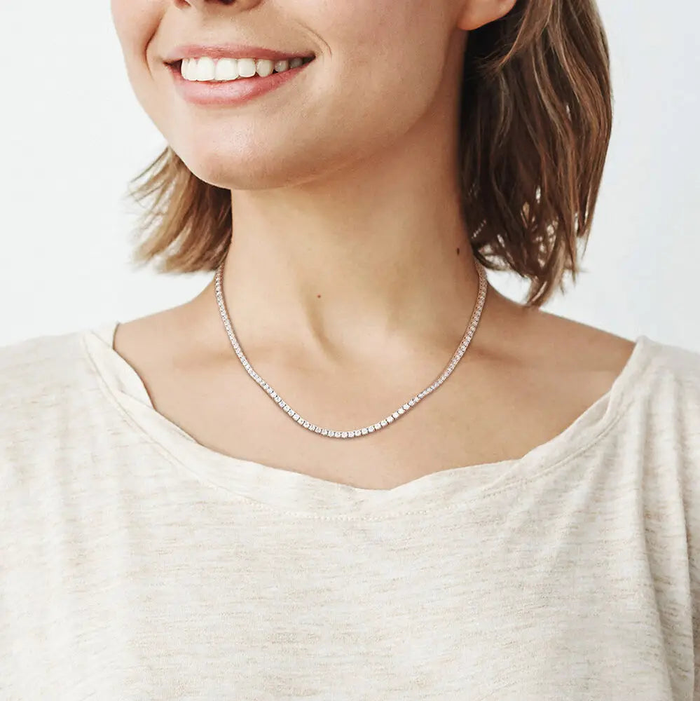 12.5 ct. DEW Created Moissanite tennis necklace featuring a continuous row of round white stones in 14K gold over brass, worn on woman