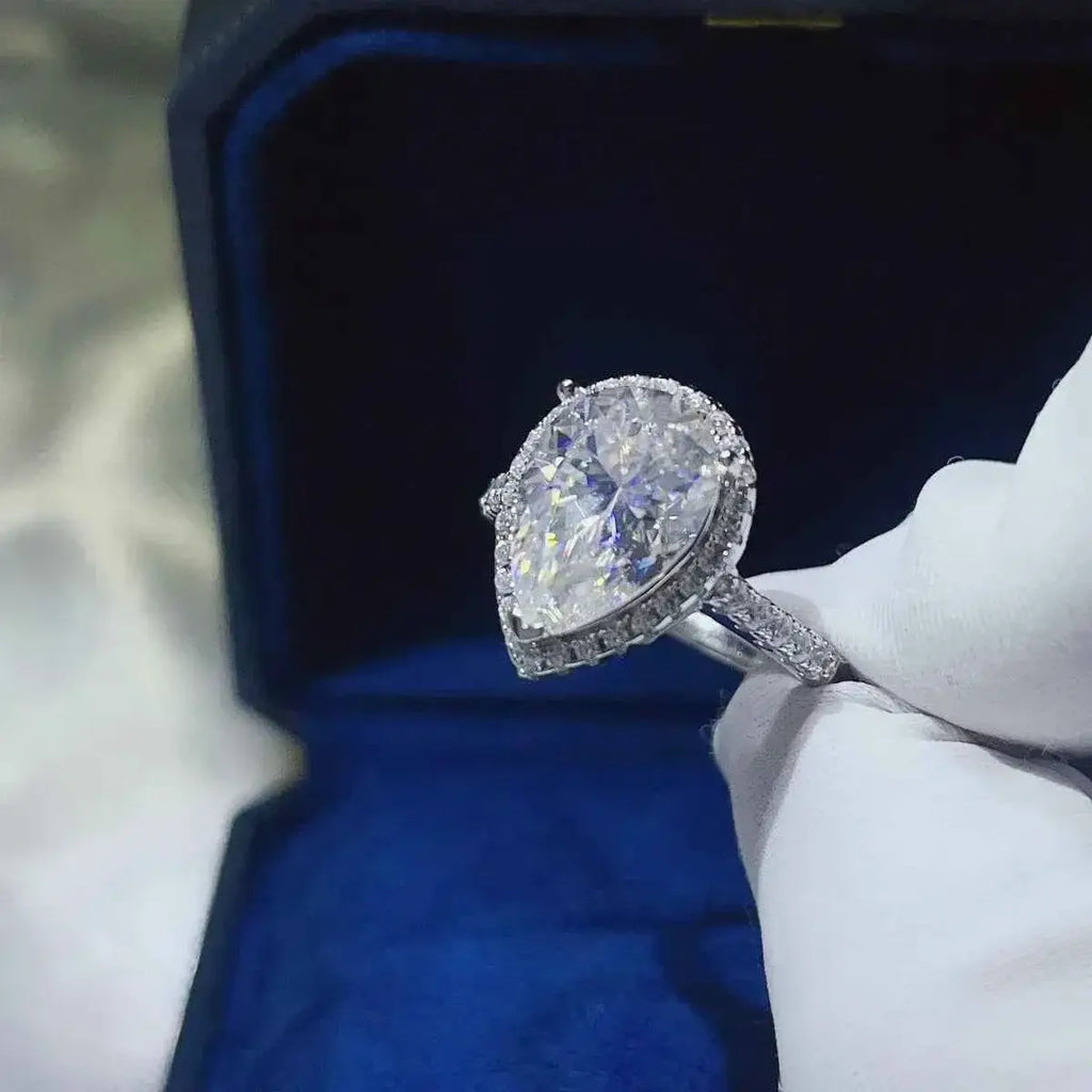 925 sterling silver ring with pear-shaped 2 Carat Moissanite center stone and smaller round stones along the band and halo setting