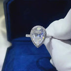 2 Carat Moissanite pear-shaped sterling silver ring with a halo of smaller stones and a pavé band design