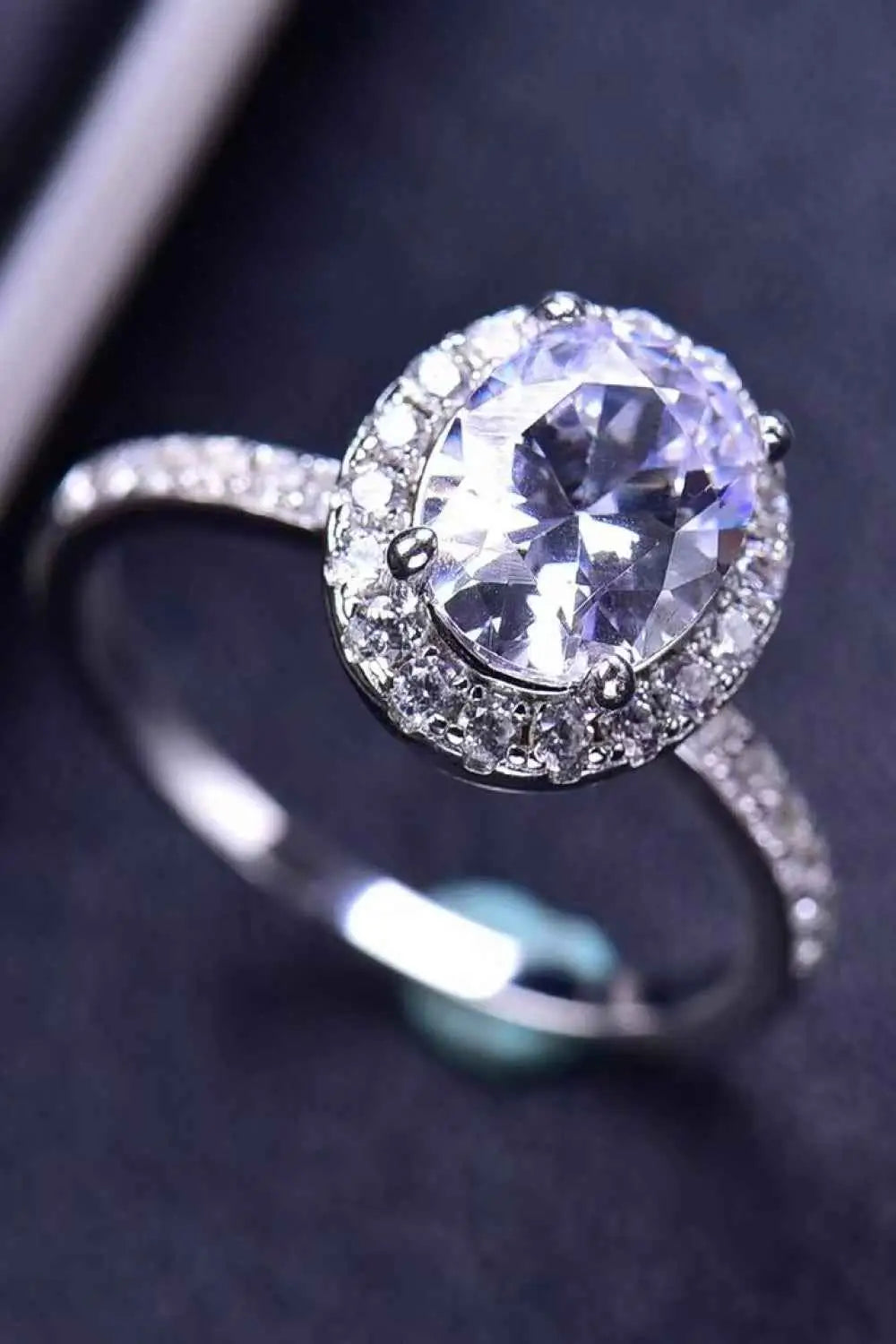 Silver platinum-plated ring featuring a large oval 2 Carat Moissanite center stone surrounded by smaller clear accent stones