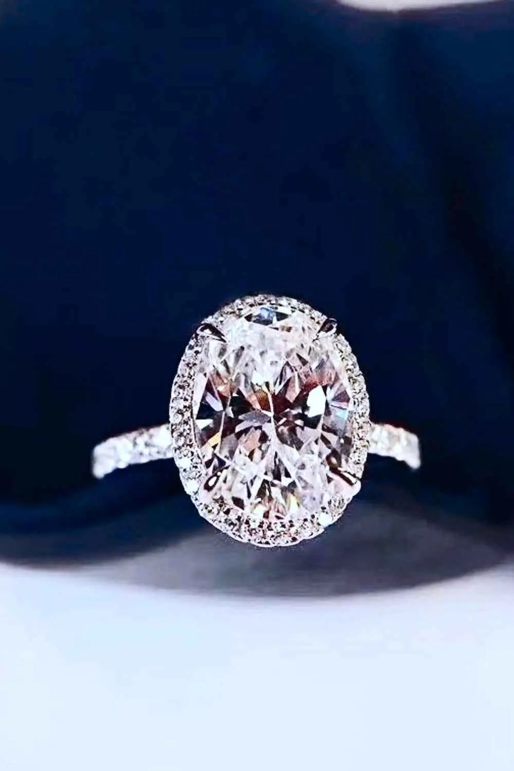 2 Carat Moissanite oval-cut ring with platinum plating, surrounded by small accent stones on a polished band