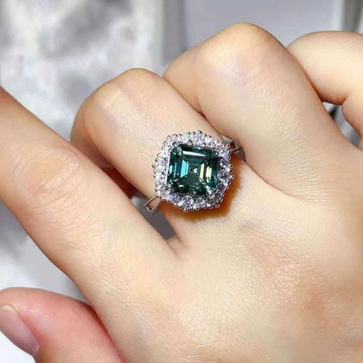 3 Carat Moissanite square-cut green stone ring with halo of small clear stones set in platinum-plated 925 sterling silver