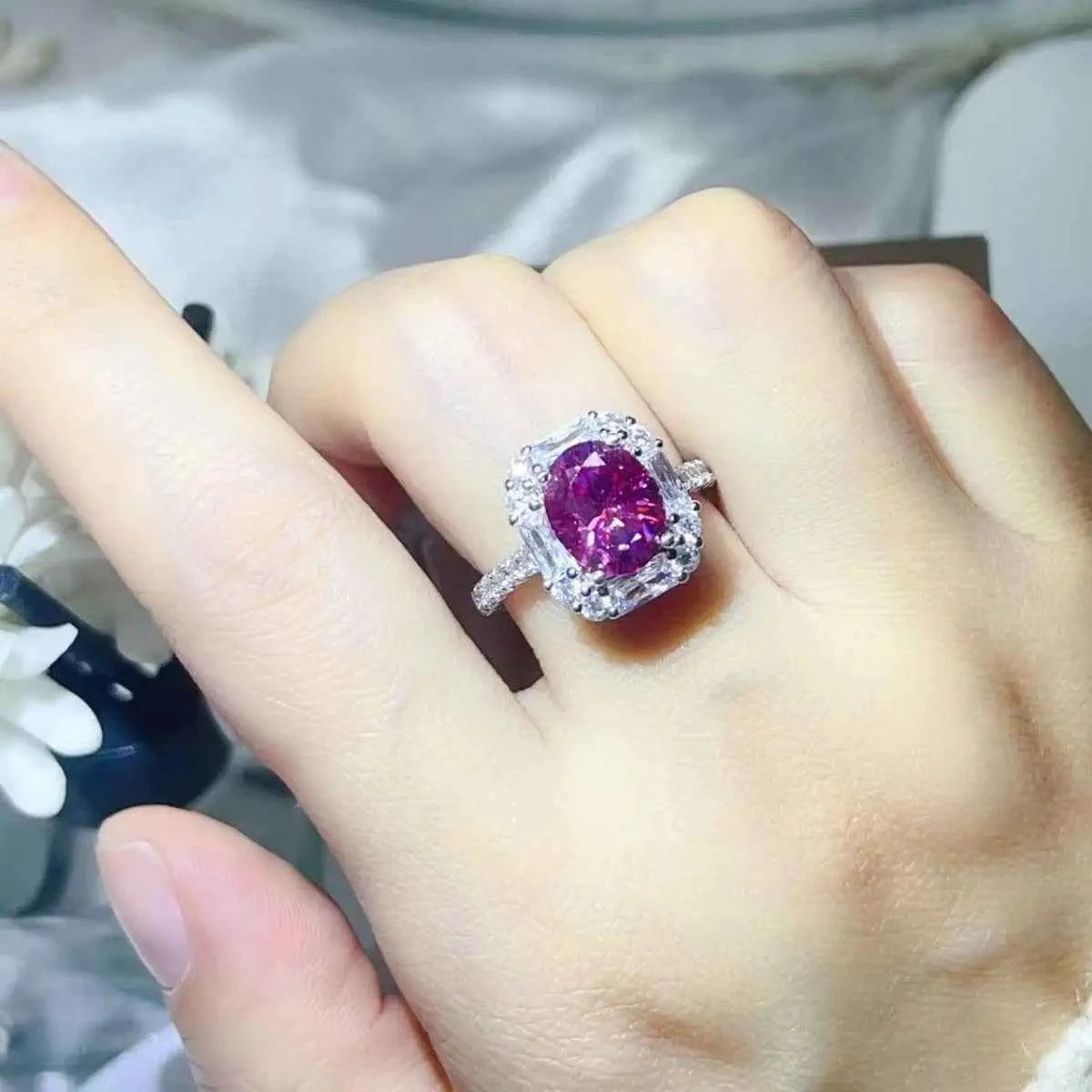 Sterling silver ring with a vibrant pink center stone surrounded by small clear stones featuring a 3 Carat Moissanite centerpiece