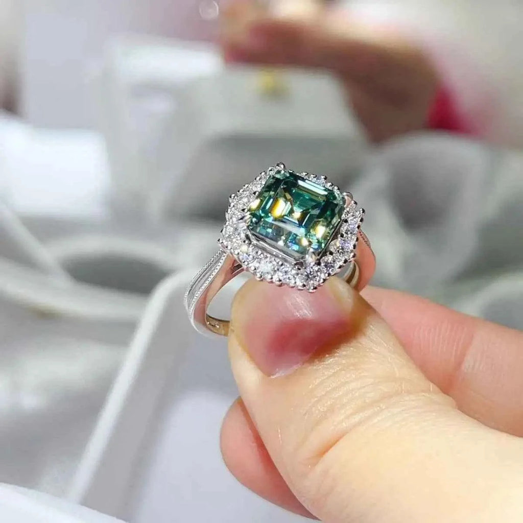 3 Carat Moissanite ring with a square-cut teal gemstone surrounded by small clear stones set in silver metal band