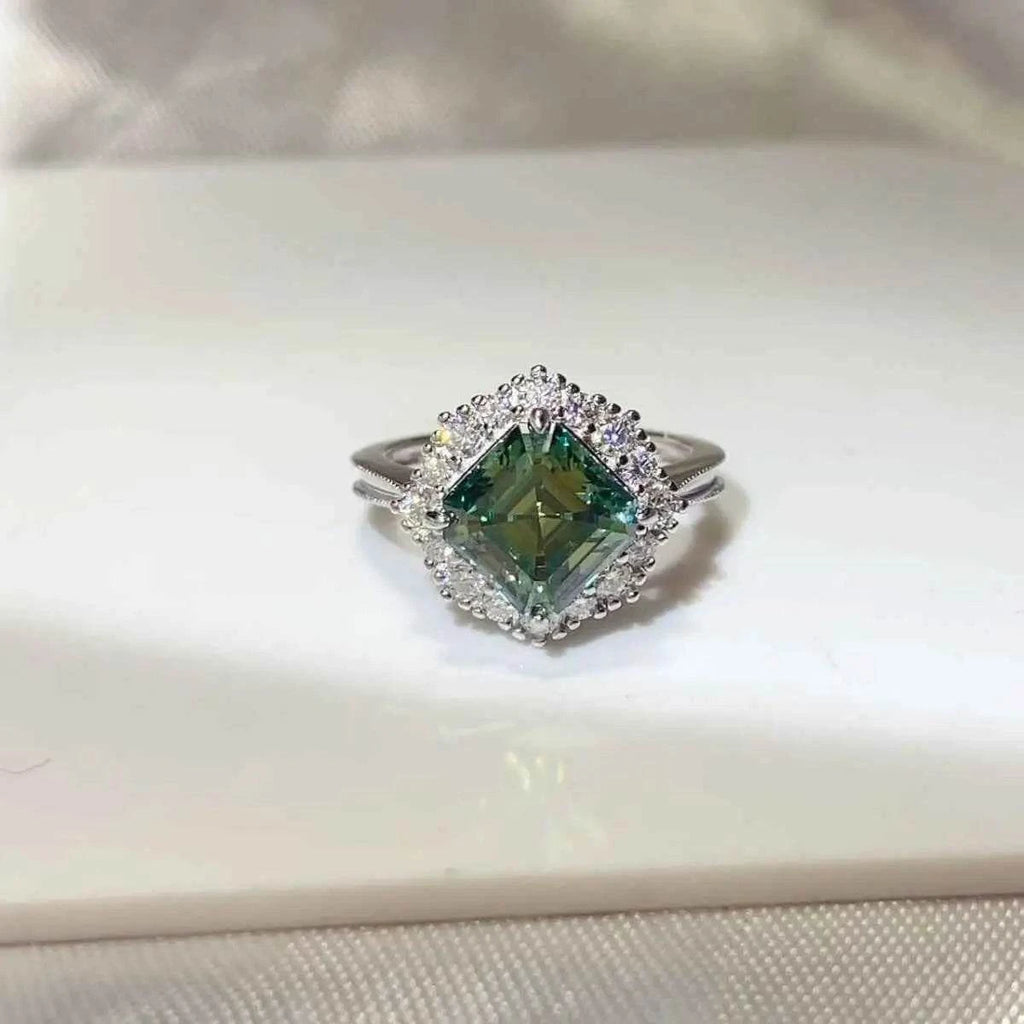 3 Carat Moissanite square cut green gemstone ring with silver band and small clear stones surrounding the center gem