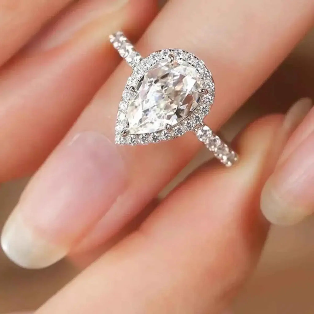 4 Carat sterling silver ring with a pear-shaped clear gemstone surrounded by small round stones on a pave band