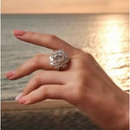 5 Carat sterling silver ring with a large round sparkling moissanite center stone surrounded by smaller stones on a delicate band