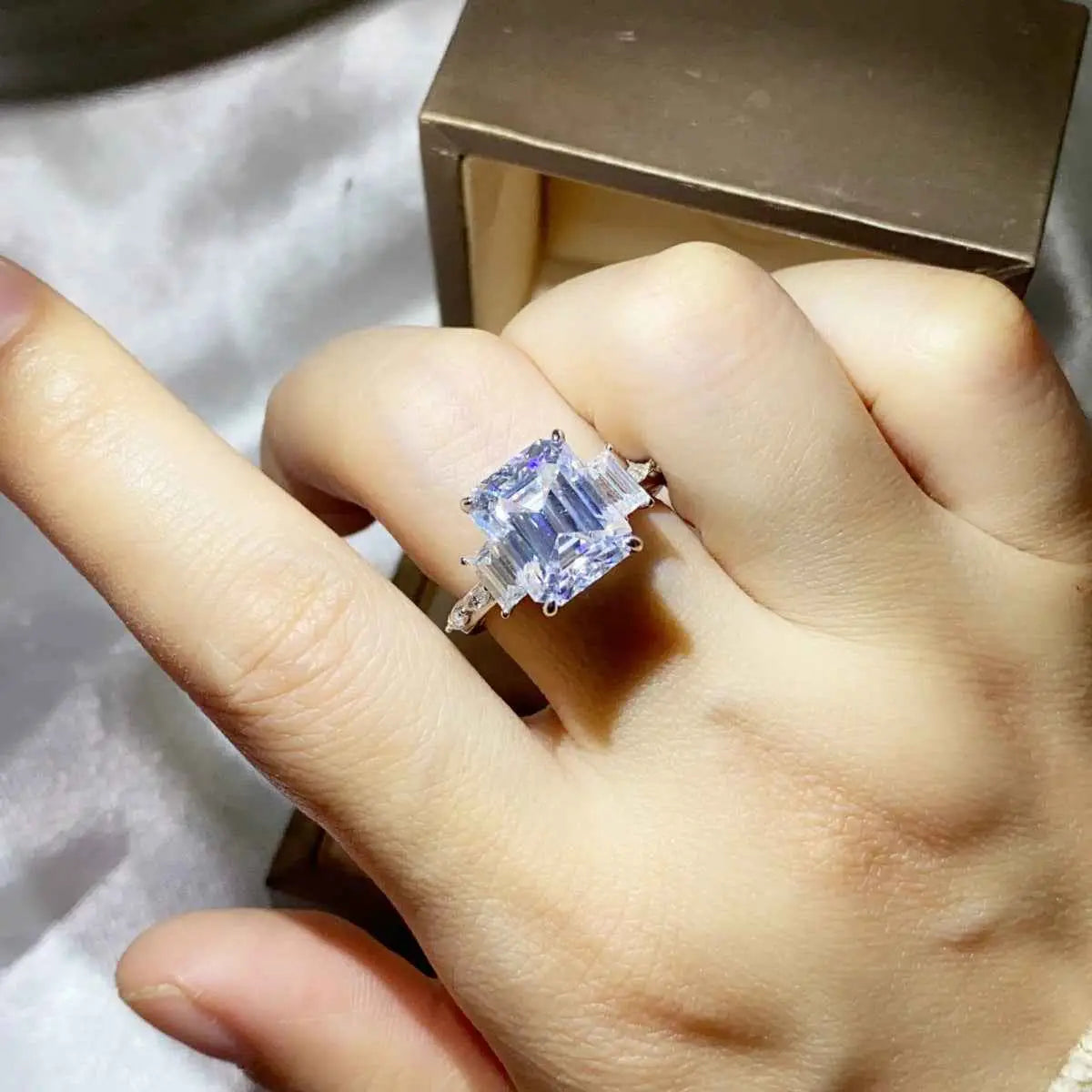 5 Carat Moissanite ring with a large rectangular clear stone set in silver with smaller side stones on a sleek band