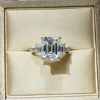 925 sterling silver ring with a large square-cut 5 Carat Moissanite center stone and baguette side stones in a beige jewelry box