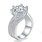 925 sterling silver ring with a large round 5 Carat Moissanite center stone and three rows of small accent stones on the band