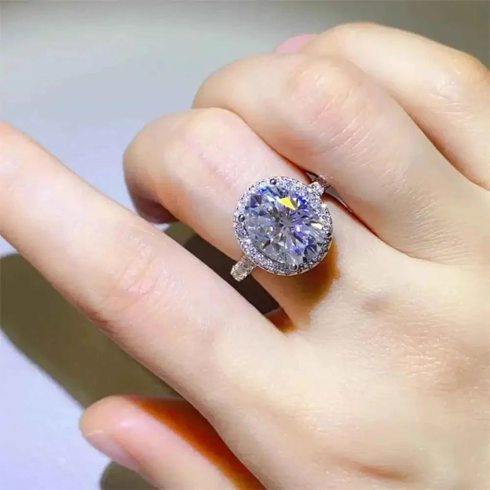 925 sterling silver ring featuring a large round 5 Carat Moissanite stone surrounded by smaller clear stones in a halo setting