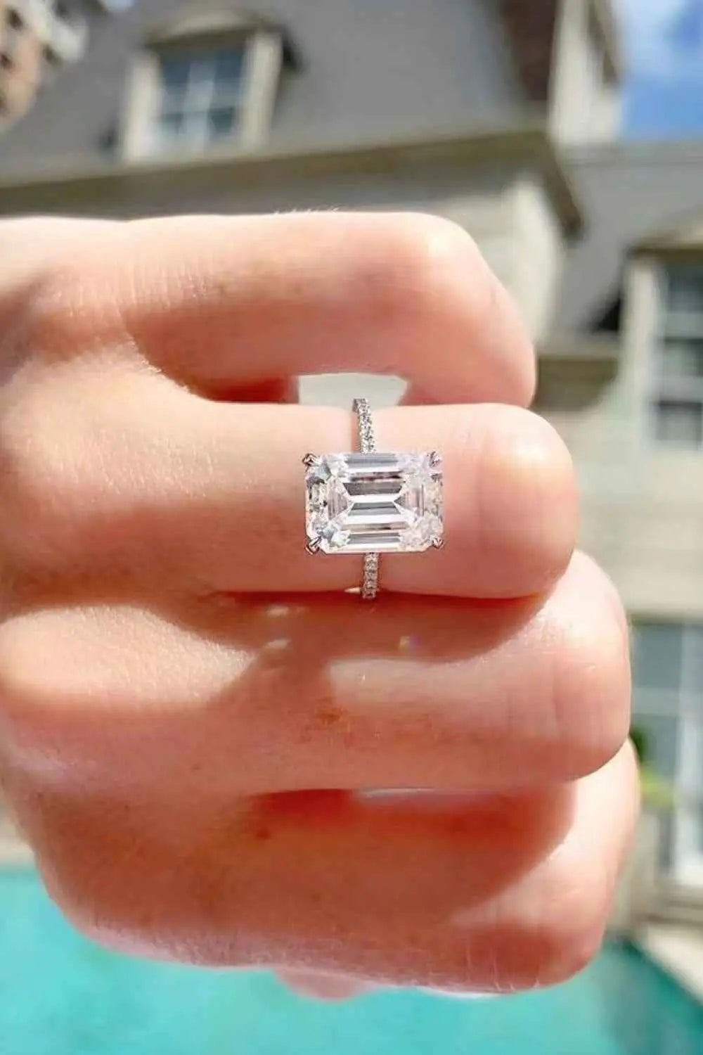 5 Carat Moissanite ring with an emerald-cut center stone and a slim platinum-plated sterling silver band adorned with small accent stones