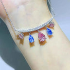 6 Carat necklace featuring 925 sterling silver with teardrop-shaped pink and blue gemstones hanging from a curved, diamond-studded bar.