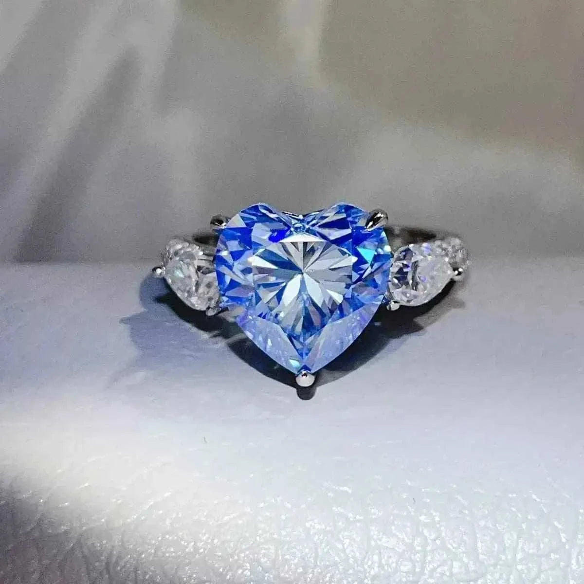 6 Carat sterling silver ring with a large blue heart-shaped center stone and two smaller clear stones on the sides
