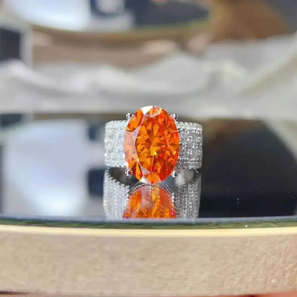 925 sterling silver ring with a large oval orange 8 Carat Moissanite center stone and pavé diamond band detailing.