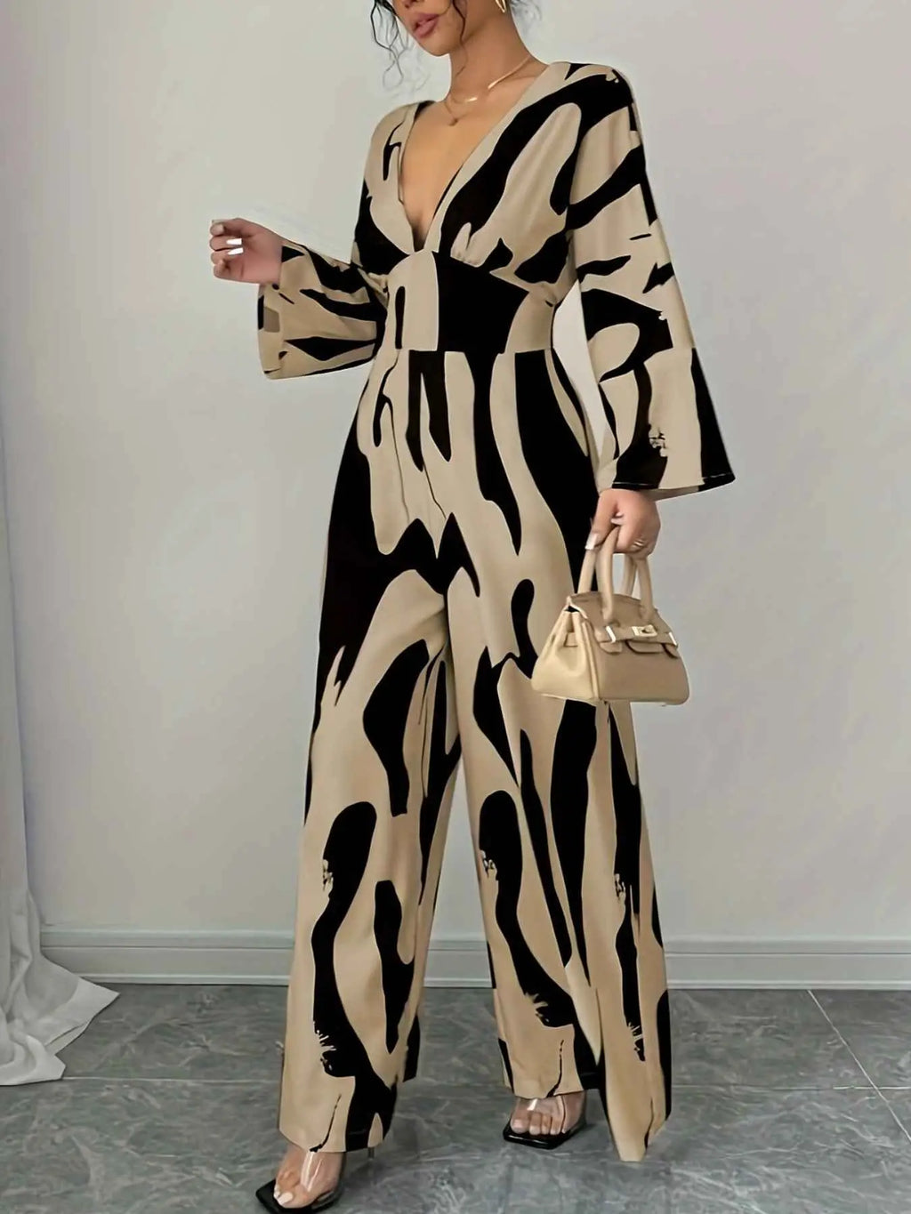 Abstract Print V-Neck jumpsuit in beige and black with wide legs, long sleeves, deep V neckline, and belted waist