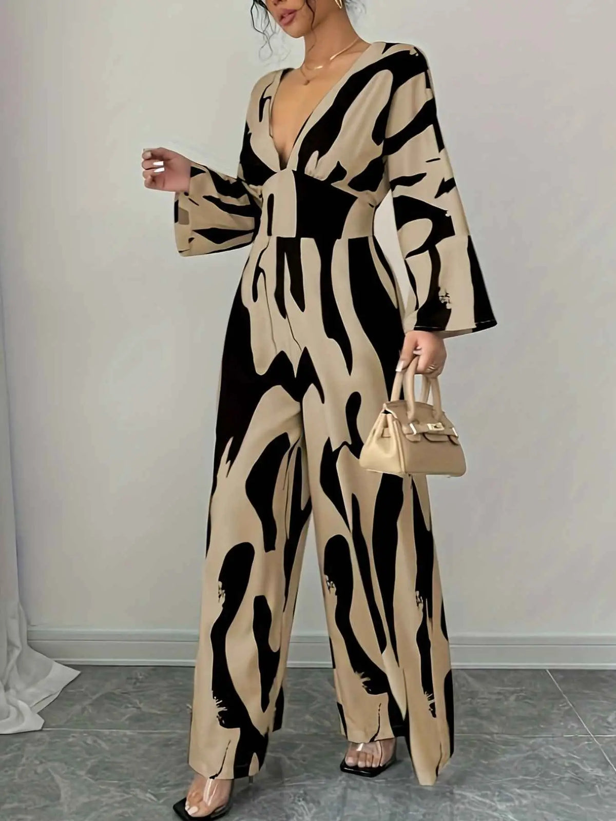 Abstract Print V-Neck jumpsuit in beige and black with wide legs, long sleeves, deep V neckline, and belted waist