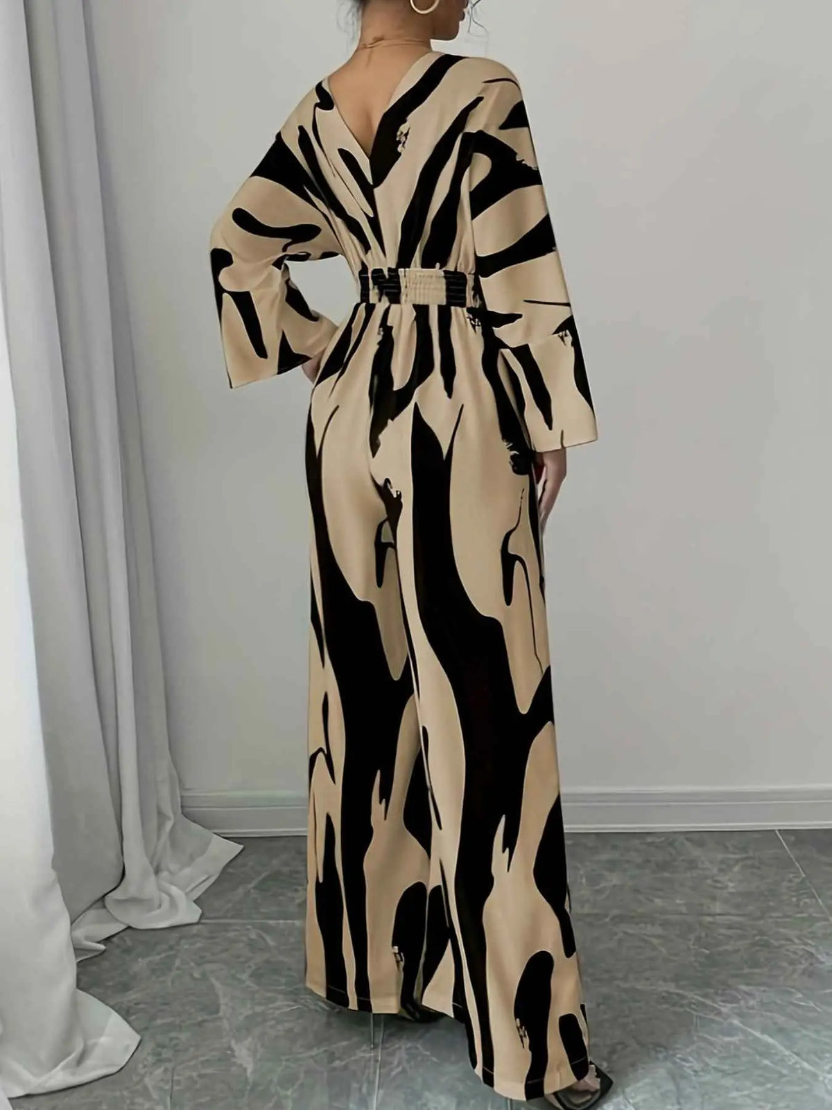 Abstract Print V-Neck wide leg jumpsuit in beige and black with abstract pattern, belted waist, long sleeves, deep V neckline