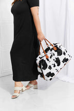 Animal Print Plush medium weekender bag with black and white cow pattern and brown top handle straps in fluff material