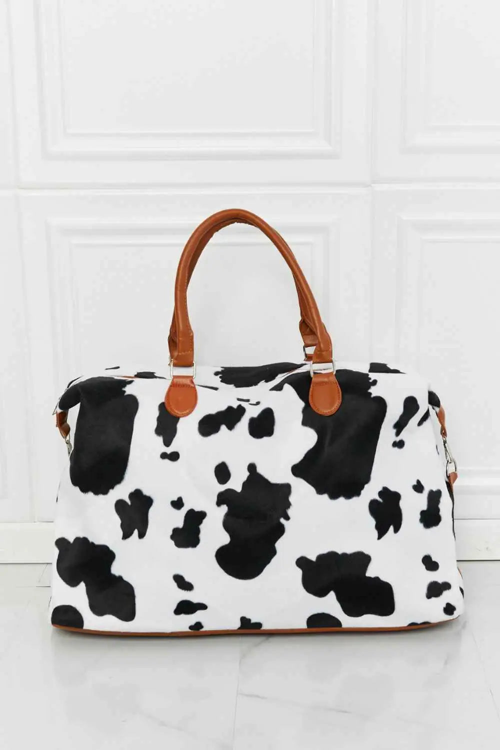 Animal Print Plush medium hand bag with black and white cow pattern and brown top handle straps in fluff material