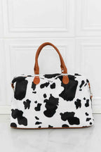 Animal Print Plush medium hand bag with black and white cow pattern and brown top handle straps in fluff material