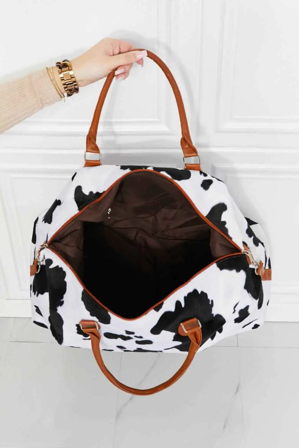 Animal Print Plush medium weekender bag with black and white cow pattern, fluff material, and brown top handles
