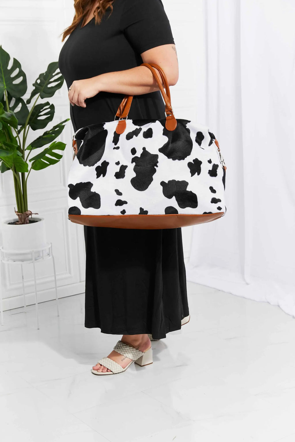 Animal Print Plush medium weekender bag with black and white cow pattern, brown top handles, and fluffy material