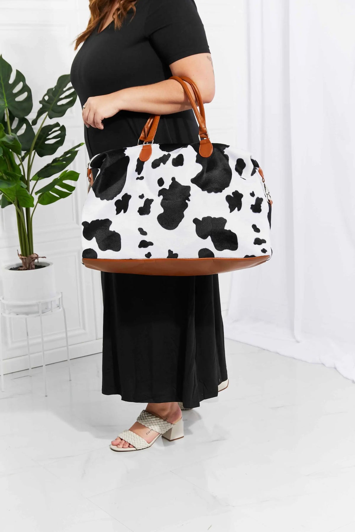 Animal Print Plush medium weekender bag with black and white cow pattern, brown top handles, and fluffy material