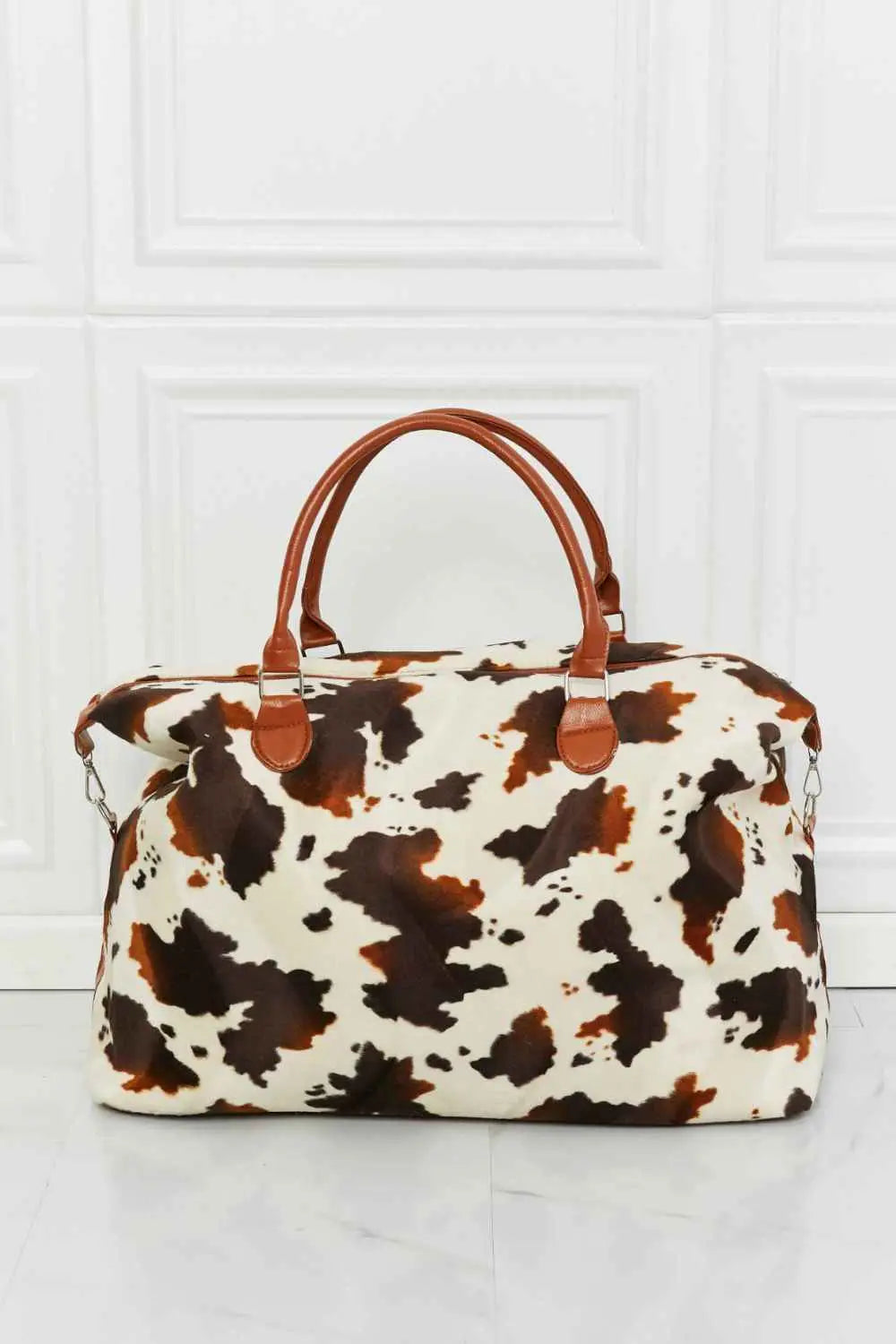 Animal Print Plush medium hand bag with brown and white cow pattern, fluffy material, and brown top handles