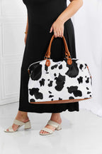 Animal Print Plush medium weekender bag in black and white cow pattern with brown leather top handles and fluffy material
