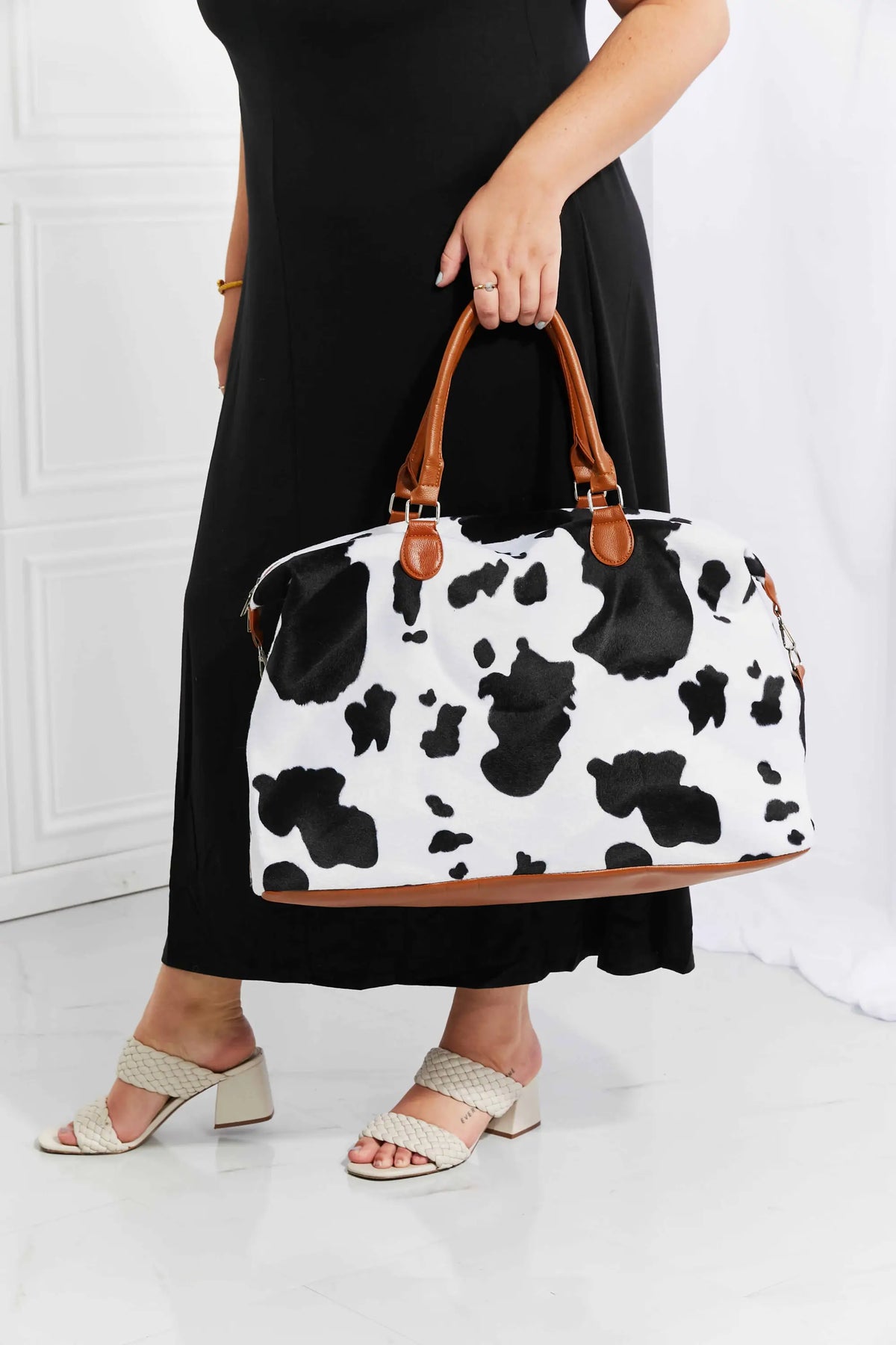 Animal Print Plush medium weekender bag in black and white cow pattern with brown leather top handles and fluffy material