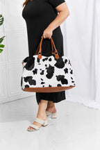 Animal Print Plush medium weekender bag with black and white cow pattern, brown faux leather handles and trim