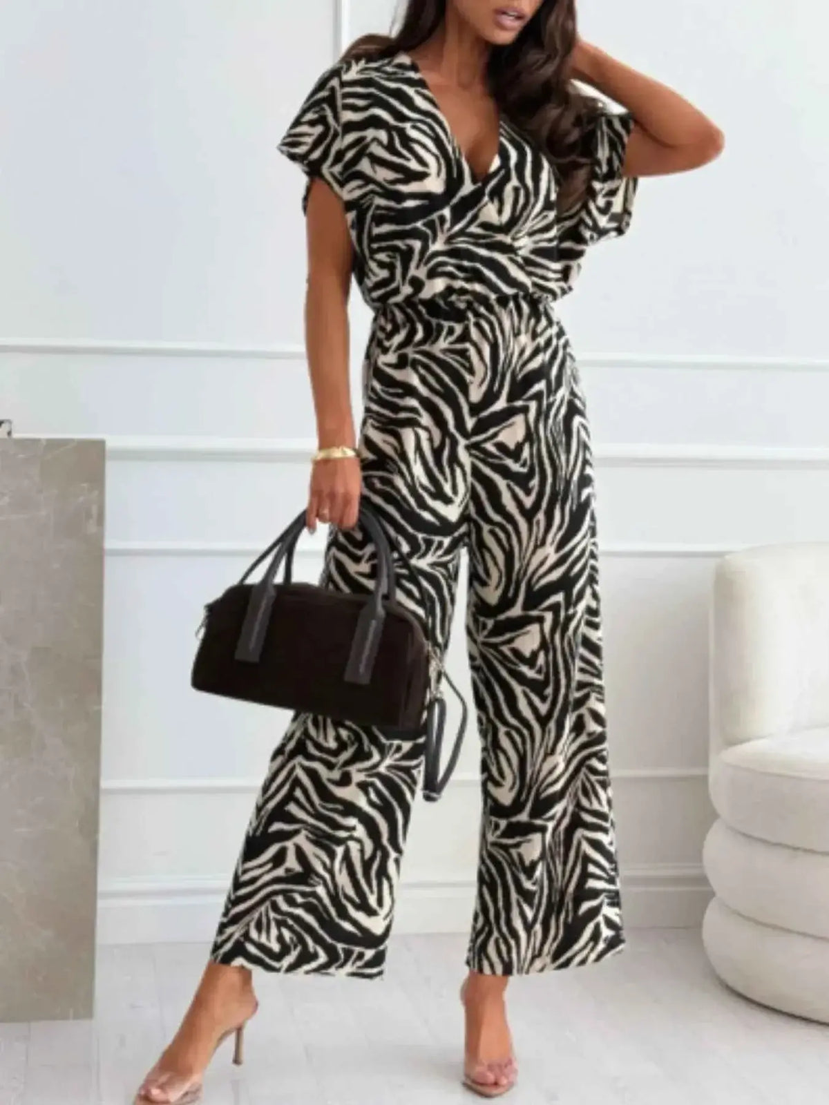 Animal Print Wide Leg Jumpsuit featuring black and white zebra pattern, short flutter sleeves, and a deep V-neckline with wide leg pants