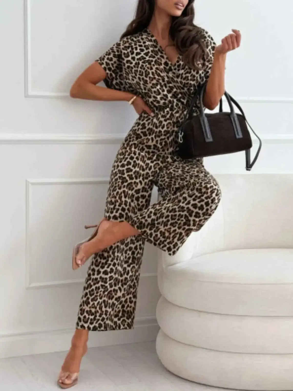 Animal Print Wide Leg Jumpsuit in leopard pattern with short sleeves and a wrap-style top paired with clear heels and black handbag