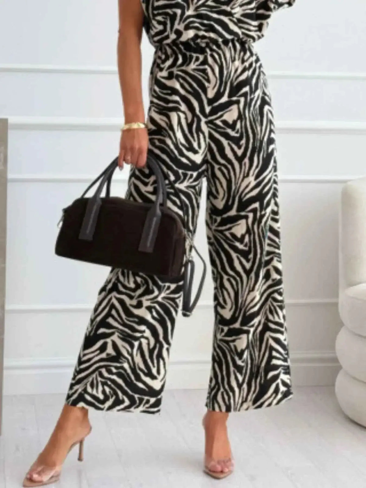 Animal Print Wide Leg Jumpsuit with black and white zebra pattern, sleeveless, loose fit, paired with a black handbag and nude heels