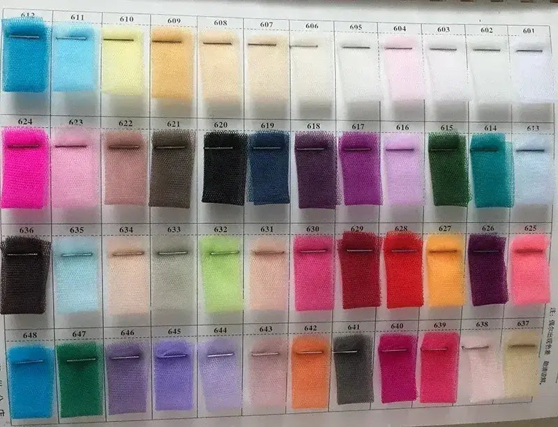 Color swatch samples showing a variety of pastel and vivid shades in fabric pieces pinned on a card for wedding dress customization