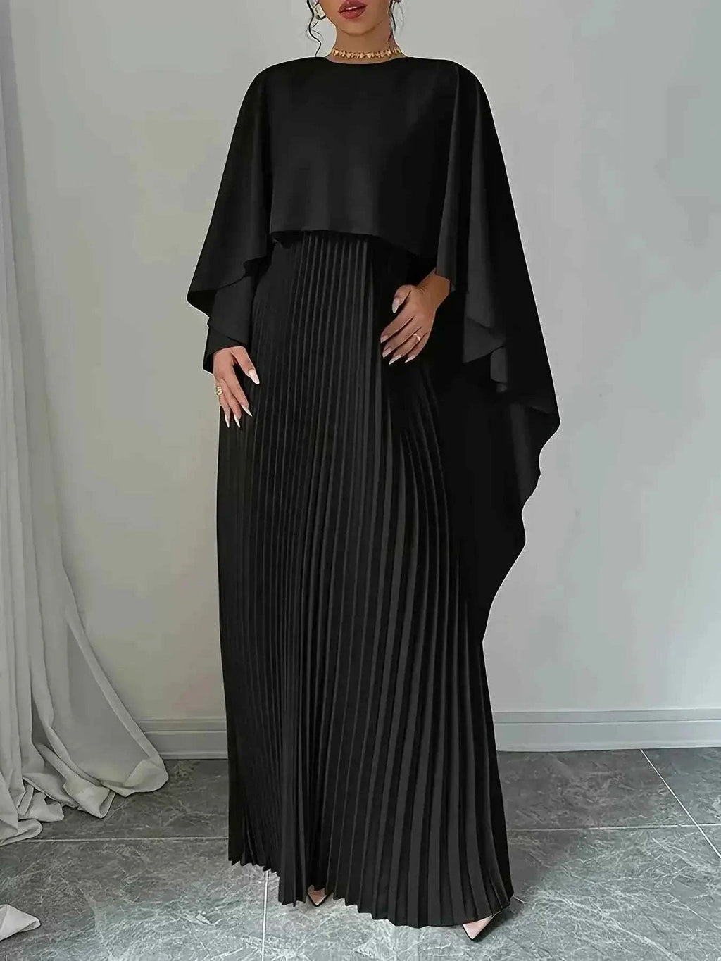 Black polyester Cape Pleated Maxi Dress with a flowing cape overlay and finely pleated maxi skirt details.