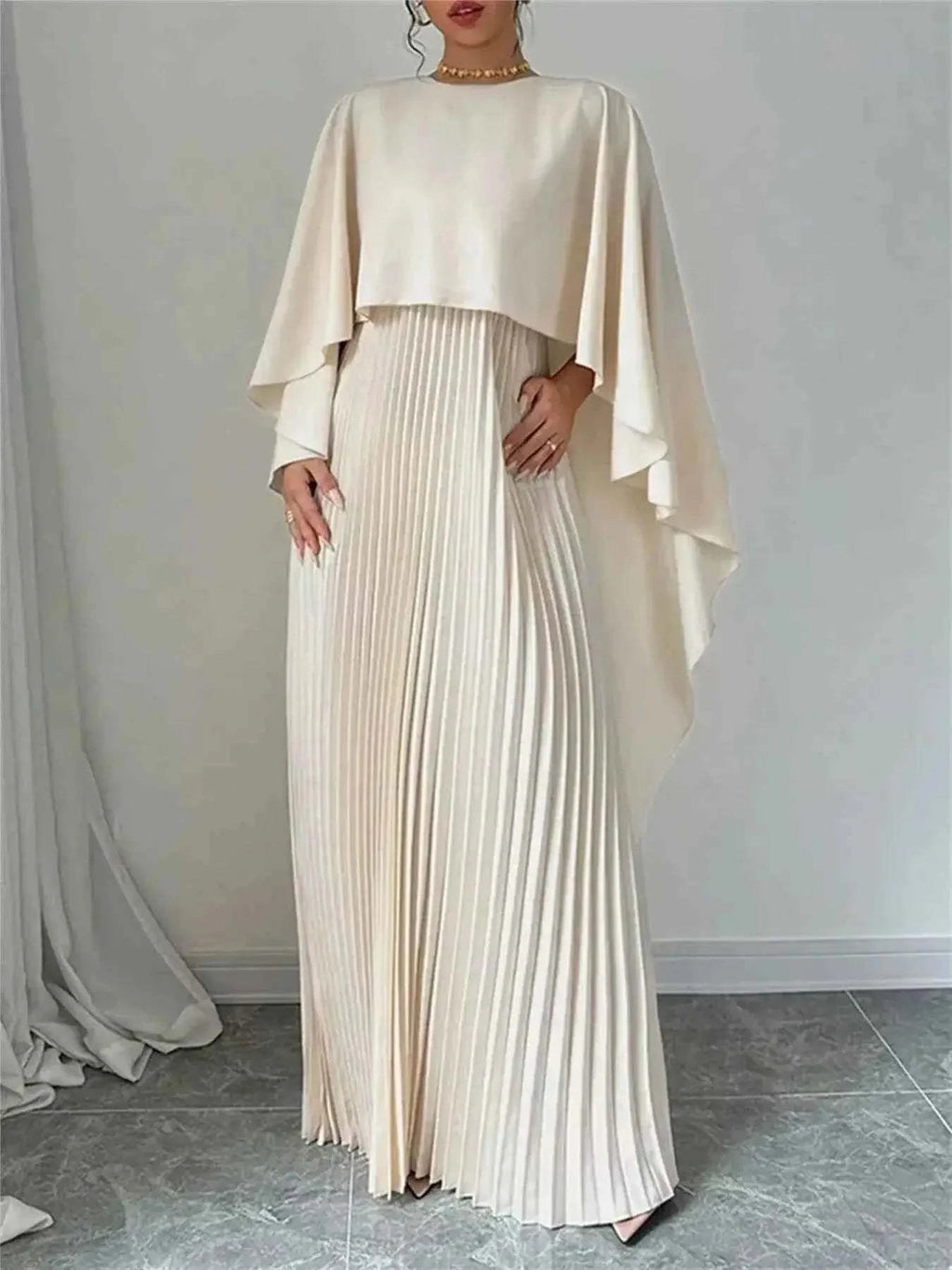 Cape Pleated Maxi Dress in cream polyester featuring a pleated skirt and a flowing cape overlay with long sleeves.