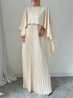Cape Pleated Maxi Dress in cream polyester featuring a pleated skirt and a flowing cape overlay with long sleeves.