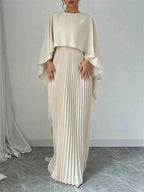 Cape Pleated Maxi Dress in cream polyester with a flowing cape overlay and finely pleated maxi skirt design.