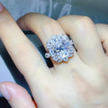 8 Carat 925 Sterling Silver ring featuring a large central moissanite stone surrounded by smaller stones in a floral cluster design.