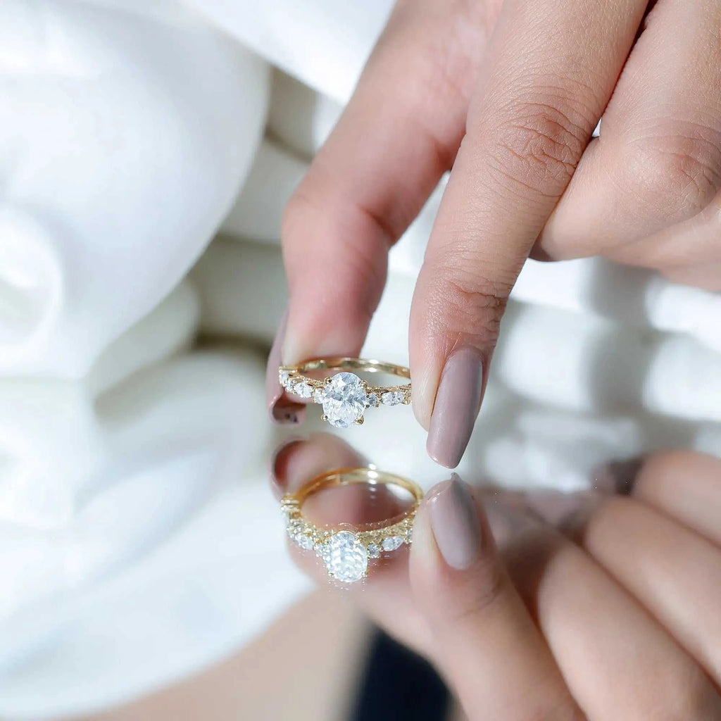 Carat IGI Certified Oval Diamond solitaire engagement ring with a gold band and side stones held between fingers